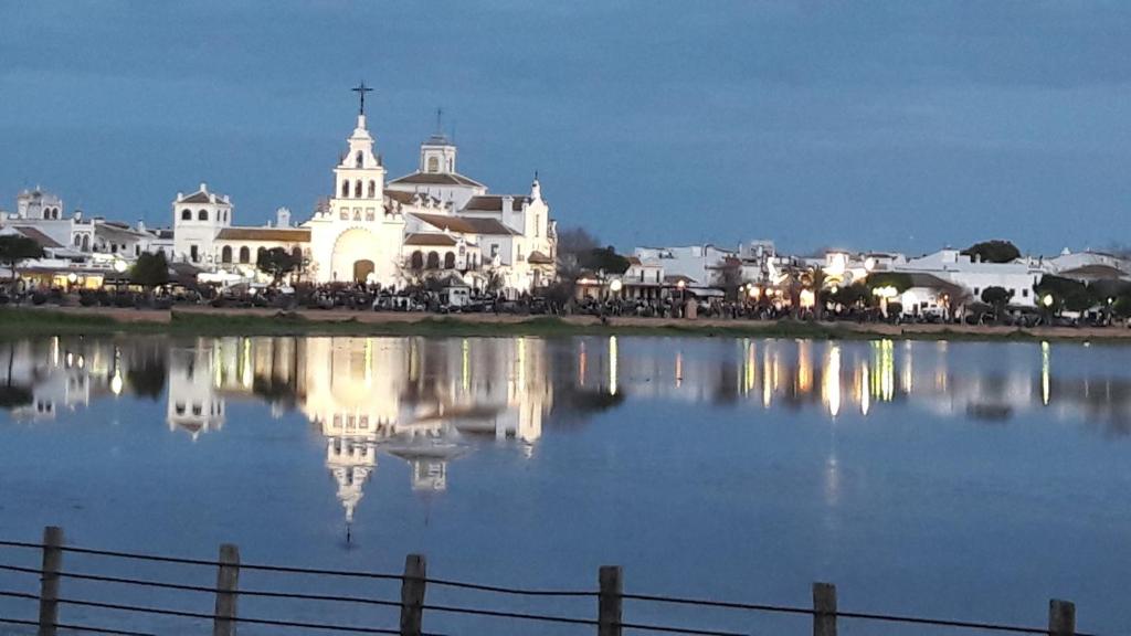 a view of a church with a reflection in the water at Jardines del Acebron in El Rocío