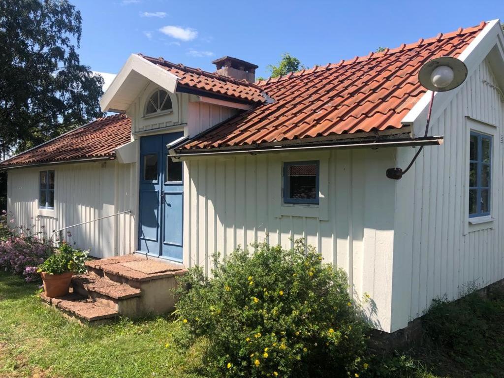 uma pequena casa branca com um telhado vermelho em Seaside Cottage Haga Park em Fröbygårda