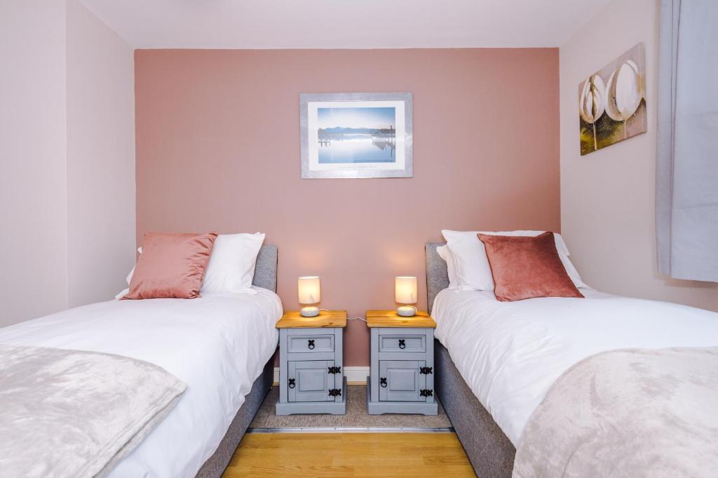 two twin beds in a room with two candles on tables at Relaxing 3 Bedroom Chester Home with garden in Broughton