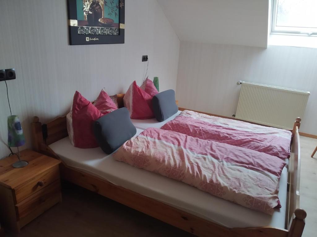 um quarto com uma cama com lençóis e almofadas cor-de-rosa em Ferienwohnung Bussard em Patersberg