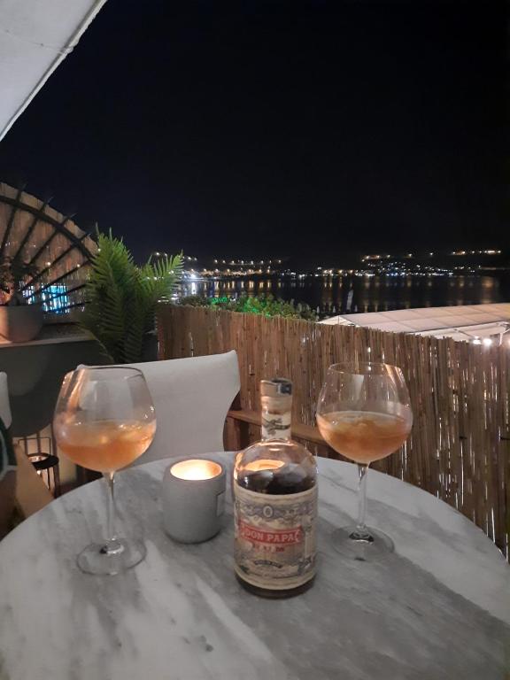 two glasses of wine sitting on a table with a candle at Billie's guest house in Iraklitsa