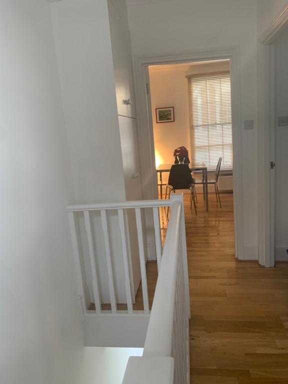 a hallway with a staircase and a dining room with a table at Beautiful one bedroom flat in the heart of Notting Hill Gate in London