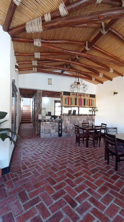 Hostería Aguas Coloradas في بورماماركا: غرفة بها طاولات وكراسي وجدار حجري