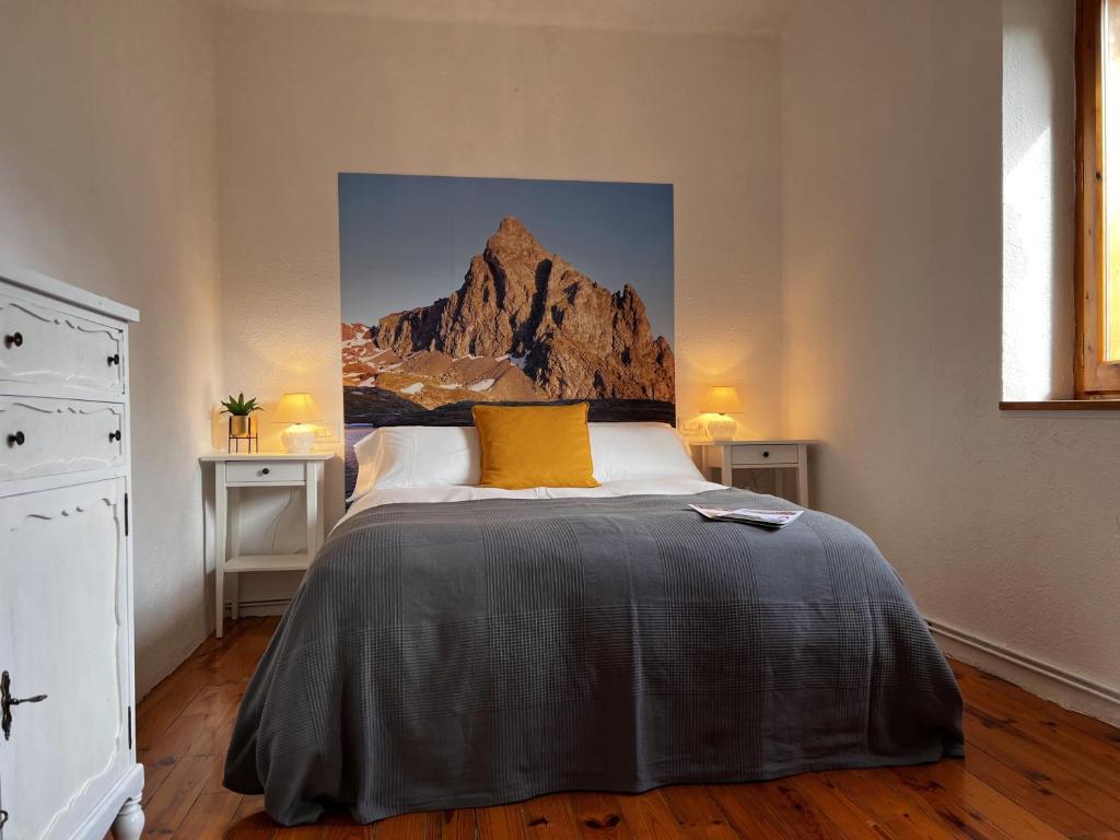 a bedroom with a bed with a painting on the wall at Cirjuana, casa en el centro con agradable jardín y barbacoa in Biescas