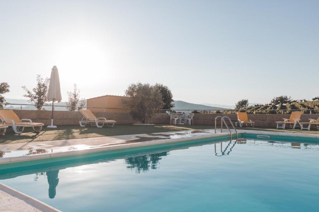 アルママールにあるCasa do Cruzeiro Quinta do Coutoの青い水と椅子付きのスイミングプール