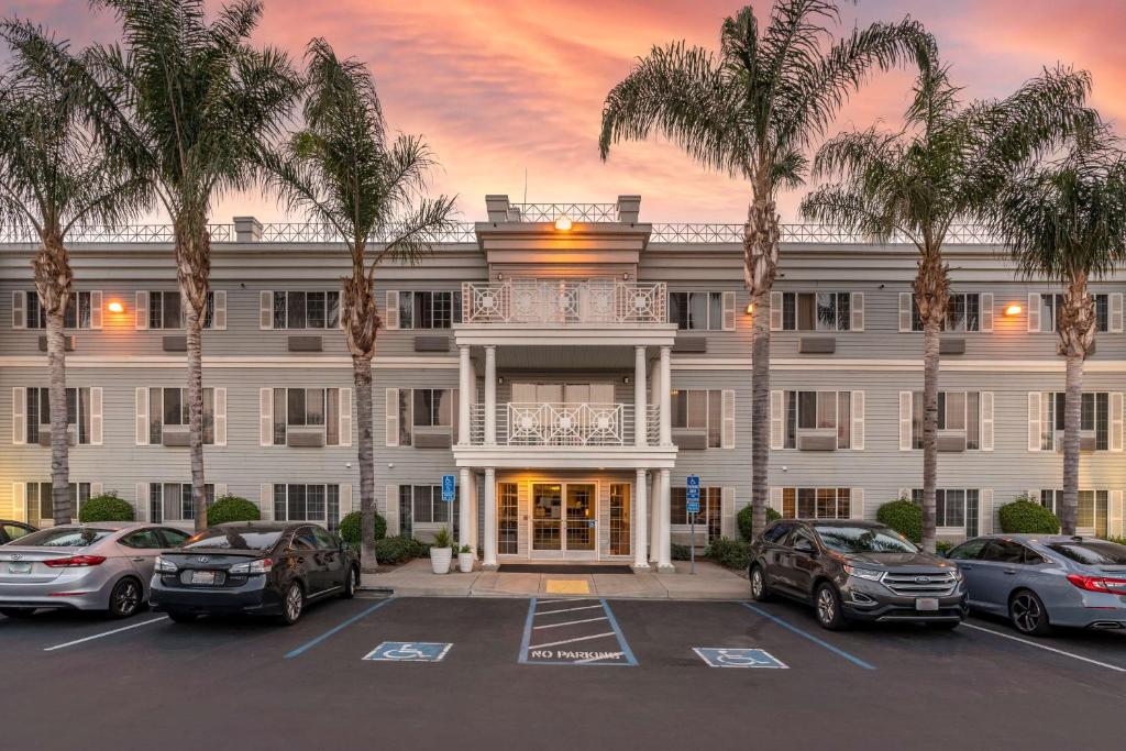 a large white building with palm trees in a parking lot at Best Western Luxury Inn in Tracy