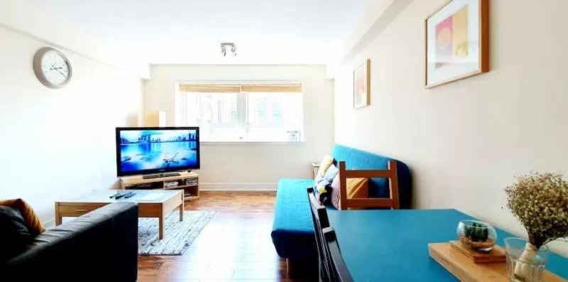 a living room with a blue couch and a tv at 2 Bedroom Apt in the Heart of the City Centre, perfect Location in Glasgow