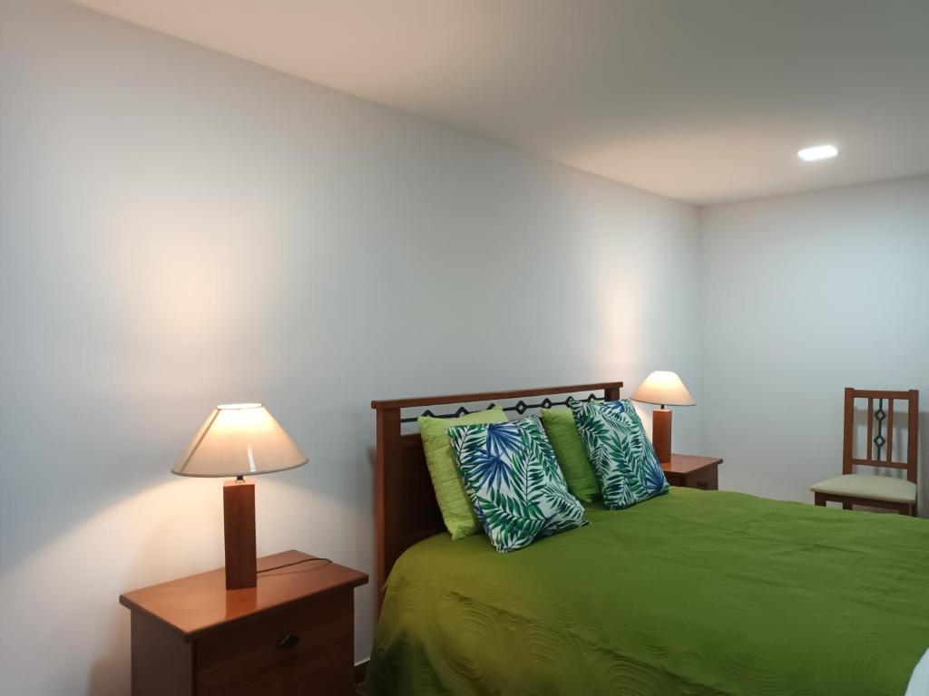 a bedroom with a green bed with two pillows at Casinha Alice in Nazaré