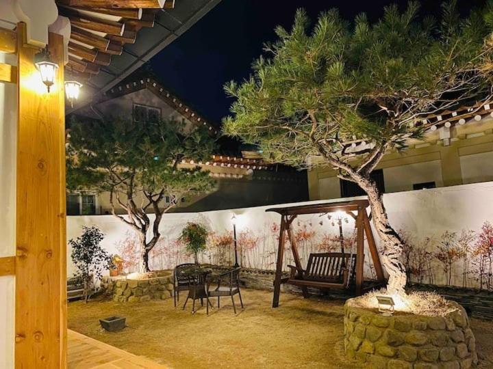 a patio with a tree and a swing at Adam Guesthouse in Gyeongju