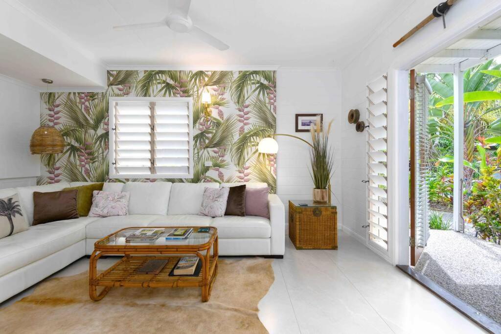 uma sala de estar com um sofá branco e uma mesa em Pandanus Place - with Bicycles em Port Douglas