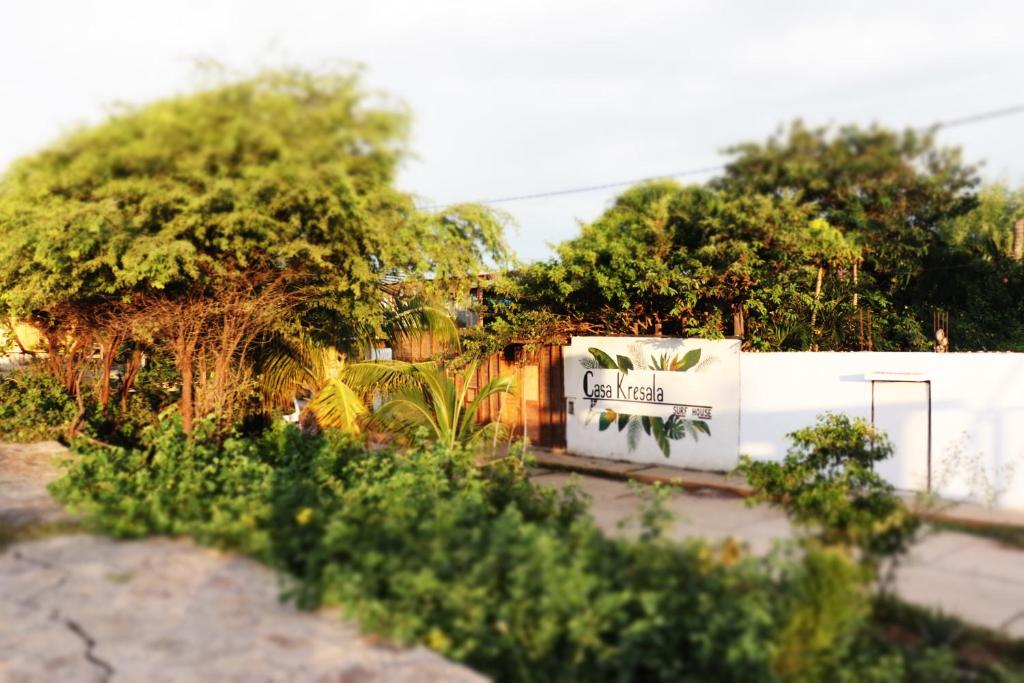 a garden with trees and plants in front of a fence at Casa Kresala, Surf House in Zorritos