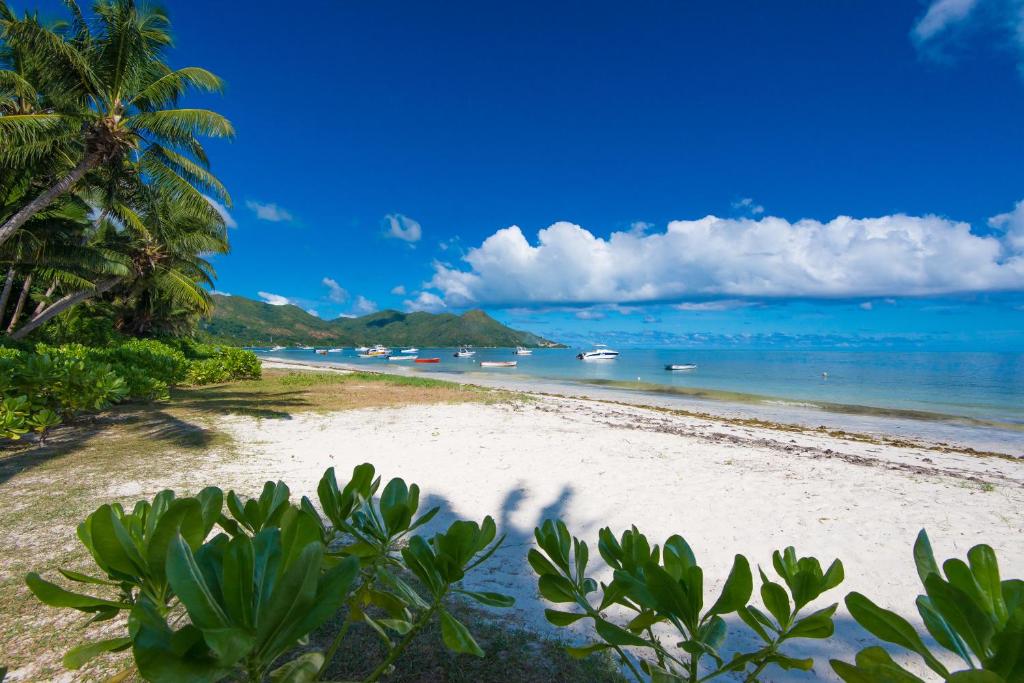 uma praia de areia com barcos na água em Le Tropique Villa em Grand'Anse Praslin