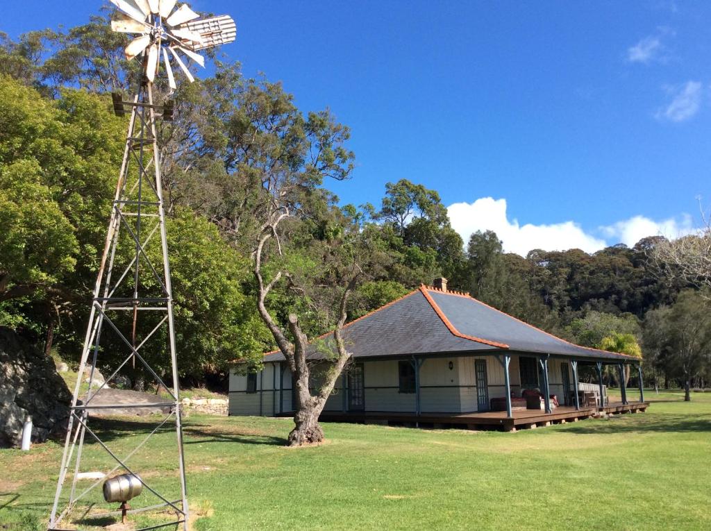 a house with a windmill in front of it at Currawong Beach Cottages in Great Mackerel Beach