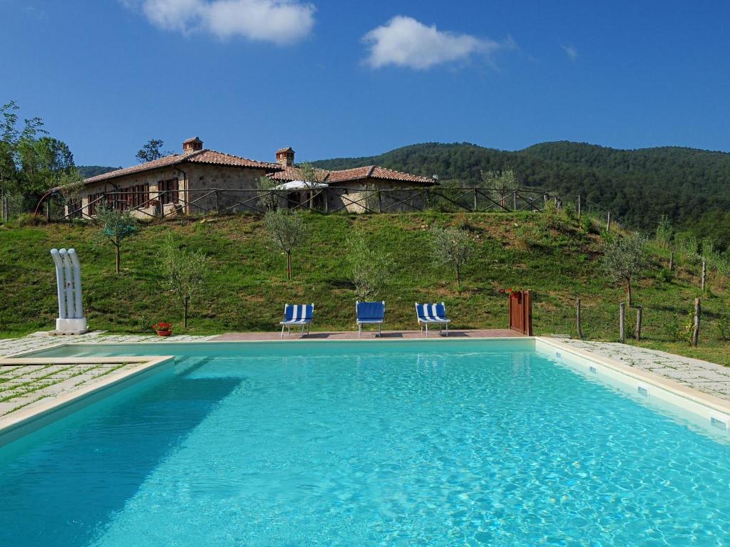 a swimming pool with chairs and a house in the background at Farmhouse with small lake swimming pool private terrace garden and sheep in Passignano sul Trasimeno