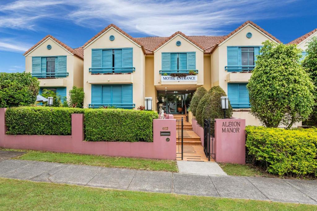 a house with blue shutters and a pink fence at Albion Manor in Brisbane