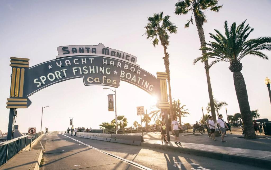 um sinal para a praia com palmeiras e pessoas caminhando em Pineapple Hostel em Los Angeles