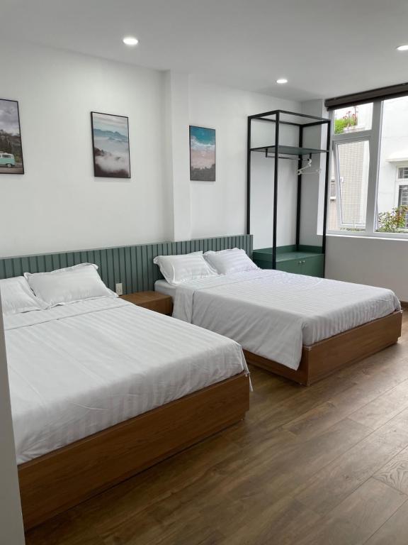 two beds in a room with white walls and wood floors at Airport homestay in Da Nang