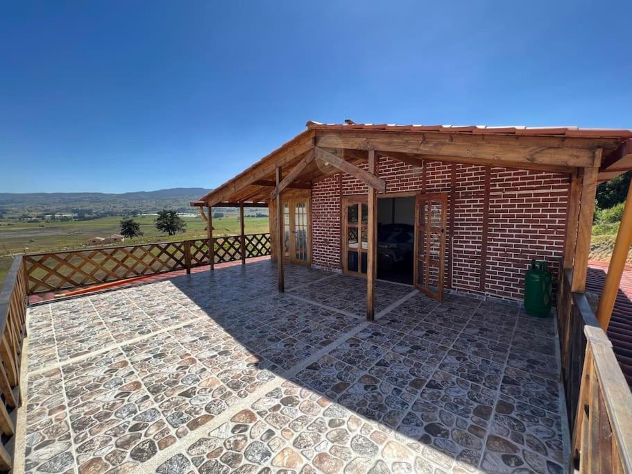 ein Backsteingebäude mit einem Holzdach und einer Terrasse in der Unterkunft Refugio Aralar EcoLodge in Toca