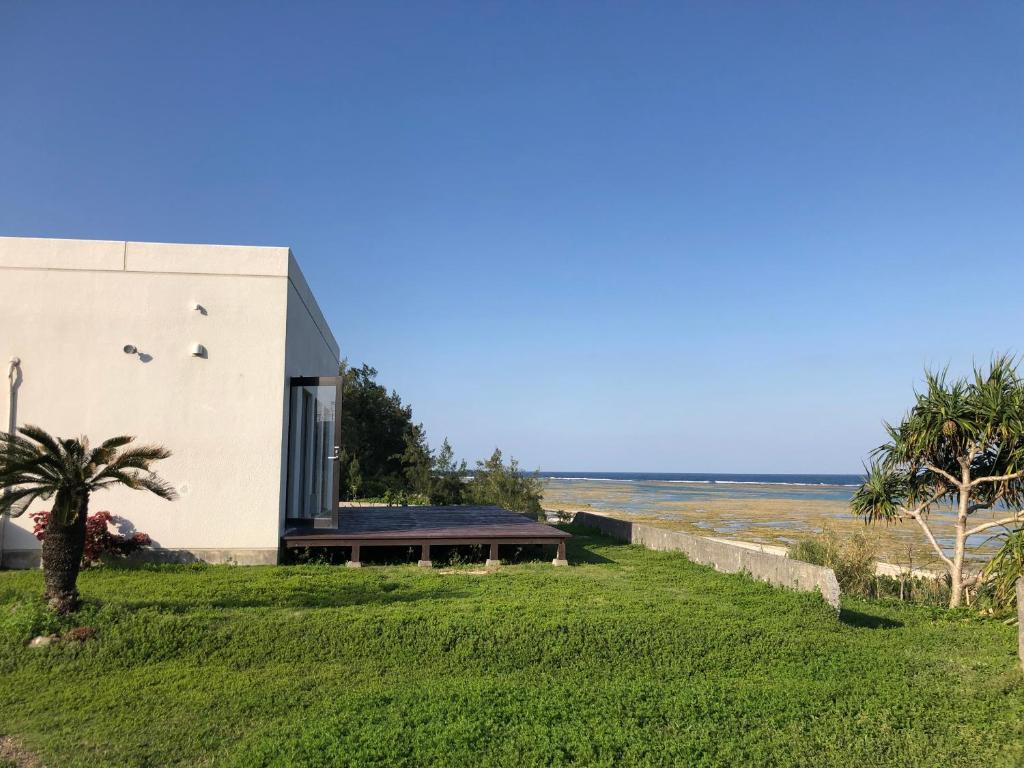 a house on the beach with a palm tree at ゴールデンマイルヴィラ in Amami