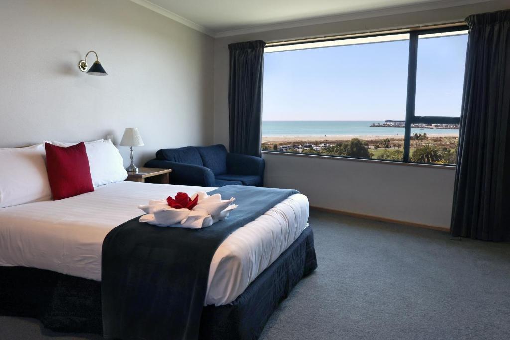 a hotel room with a bed and a large window at Baywatch Motor Lodge in Timaru