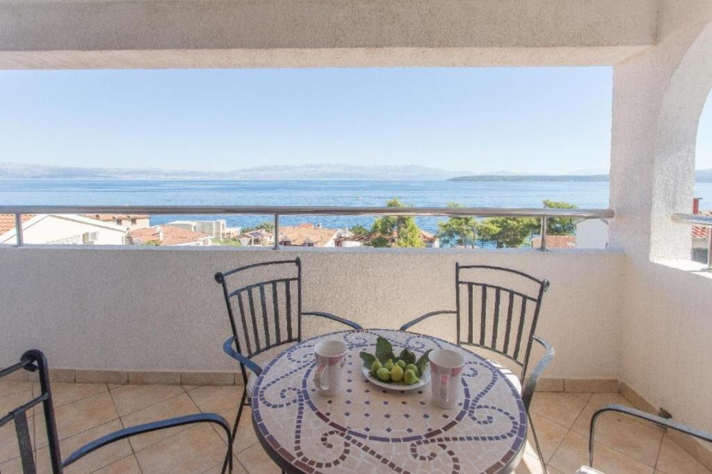 una mesa y sillas en un balcón con vistas al océano en Apartments Sanda - 100m from sea, en Stomorska