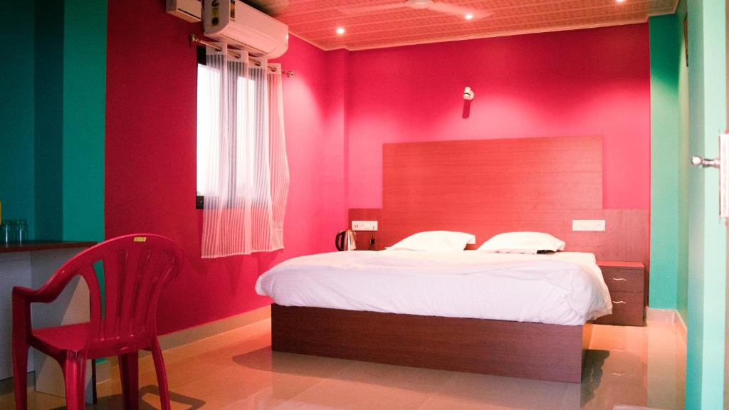 ein rotes Schlafzimmer mit einem Bett und einem roten Stuhl in der Unterkunft Malar inn in Port Blair