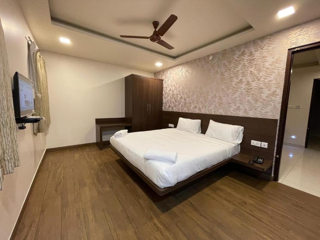 HOTEL VINTAGE CASTLE في كويمباتور: غرفة نوم بسرير أبيض مع مروحة سقف