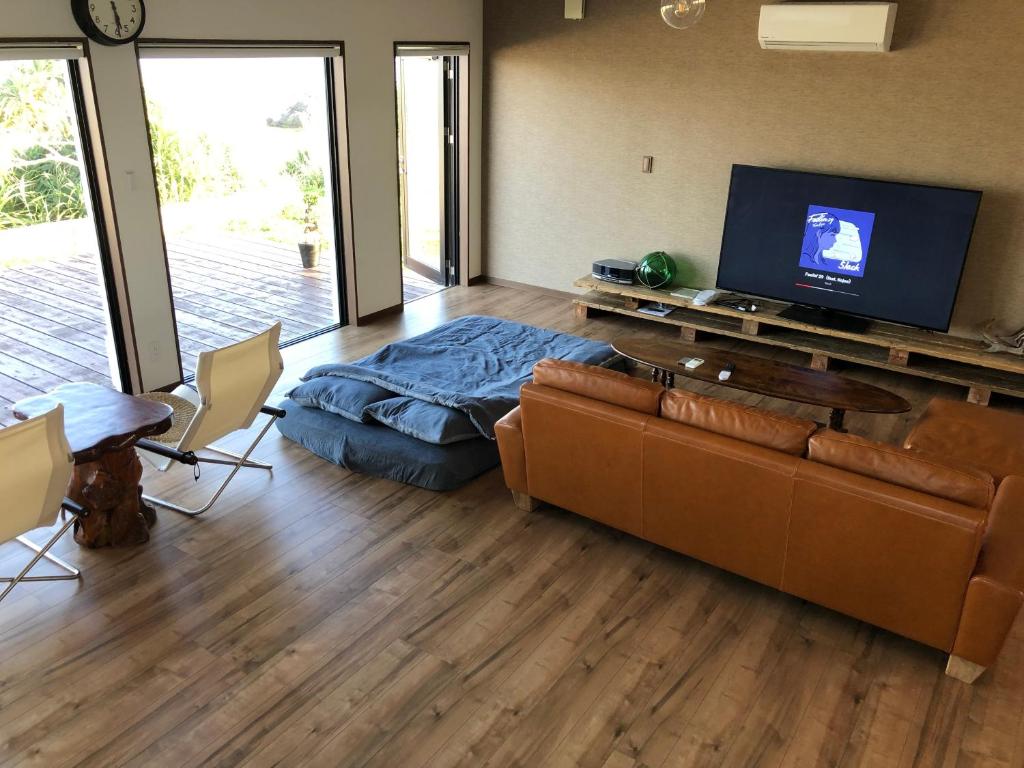 a living room with a couch and a flat screen tv at ゴールデンマイルヴィラ in Amami