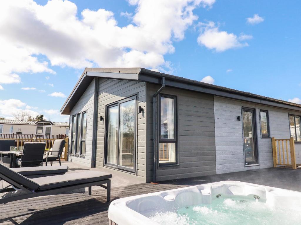 a tiny house with a hot tub on a deck at Acorn Lodge in Redruth