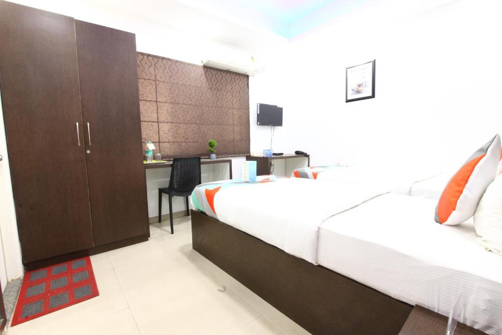 a bedroom with a bed and a desk with a chair at Avenue Inn in Bangalore
