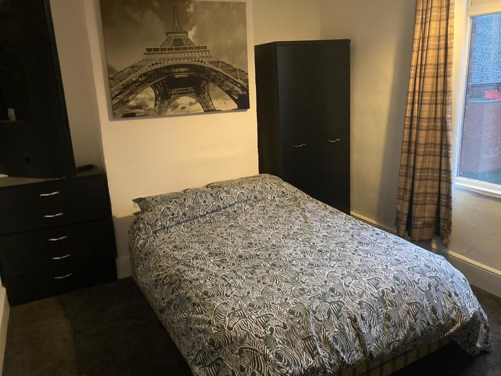 a bedroom with a bed and a picture of the eiffel tower at Trevor And The Cats in Mansfield
