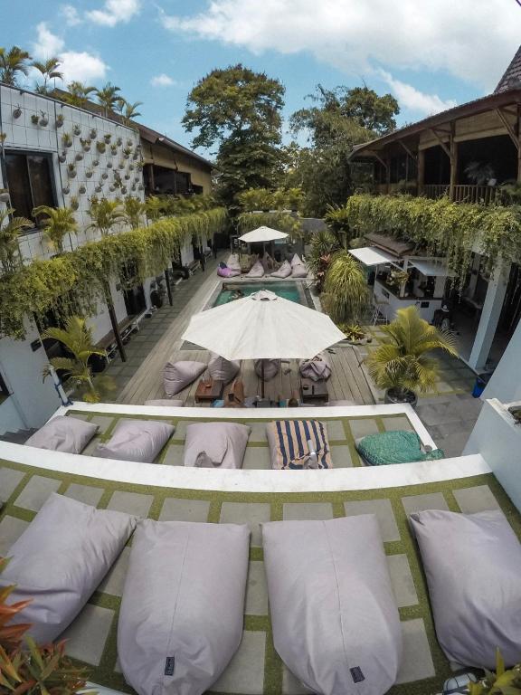 een buitenterras met kussens en een parasol bij The Farm Hostel in Canggu