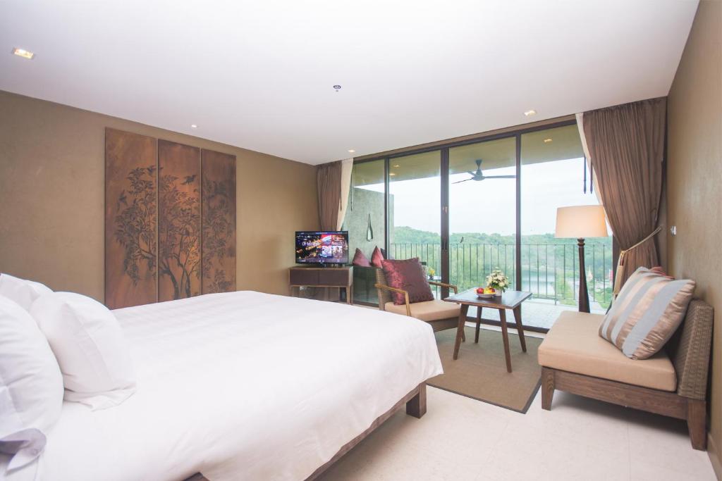 a bedroom with a large white bed and a balcony at Sunsuri Phuket - SHA Plus in Nai Harn Beach