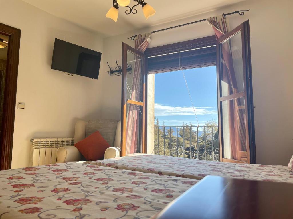 a bedroom with a bed and a large window at Hotel Rural Poqueira II in Capileira