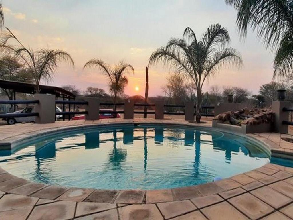 a large swimming pool with a sunset in the background at Alamo Guest Farm in Warmbaths
