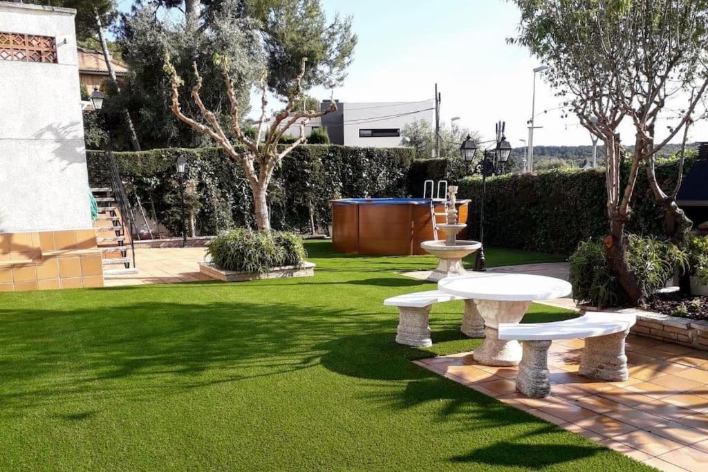un jardín con dos bancos blancos en el césped en Family House - La Mora Beach - Tarragona, en Tarragona