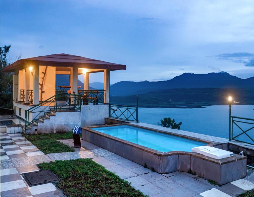 a swimming pool with a gazebo next to the water at SaffronStays Blue Infinitum, Pawna in Lonavala