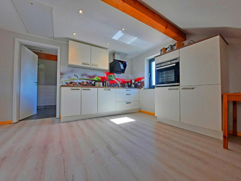 a large kitchen with white cabinets and a wooden floor at Ferienwohnung Auszeit Objekt ID 13178-9 in Waren