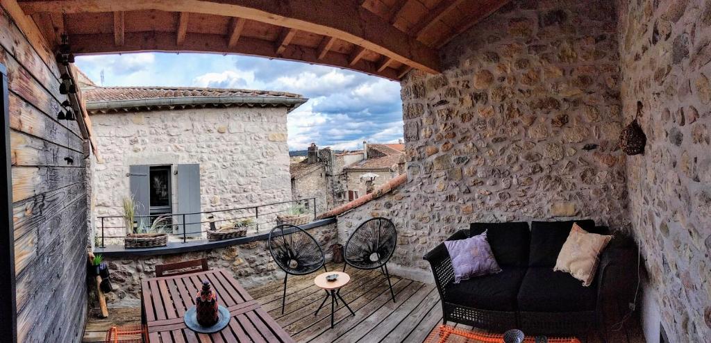 a balcony with a couch on a stone wall at Gîte de charme au coeur de Ruoms avec terrasse in Ruoms