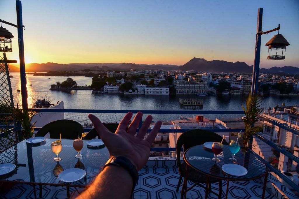 a person sitting at a table with their hand in the air at Hotel Casa by the lake in Udaipur