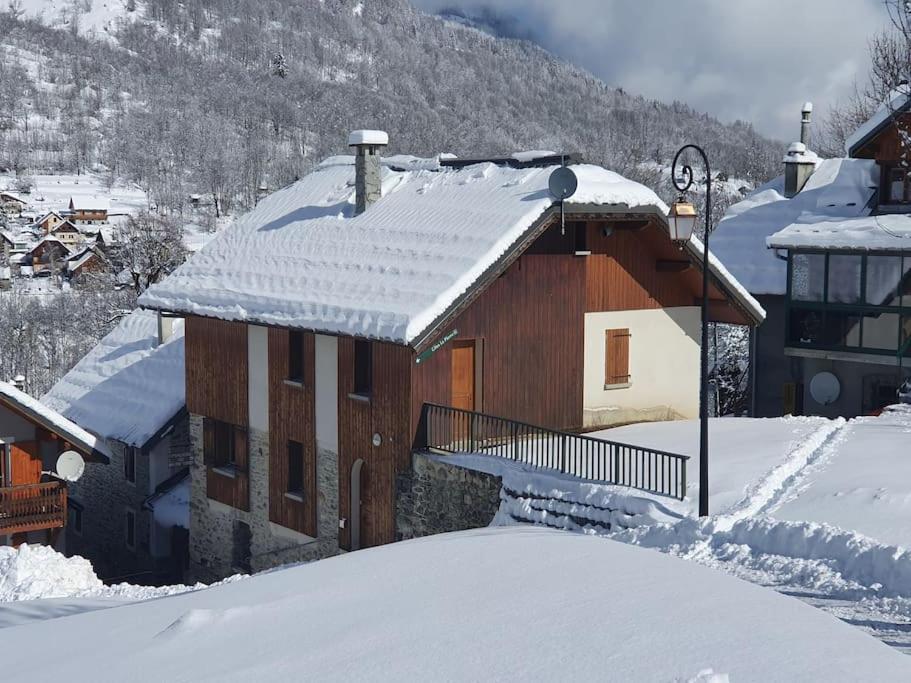 dom pokryty śniegiem z zadaszonym dachem w obiekcie Gîte d'étape La Pierre w mieście Saint-Colomban-des-Villards