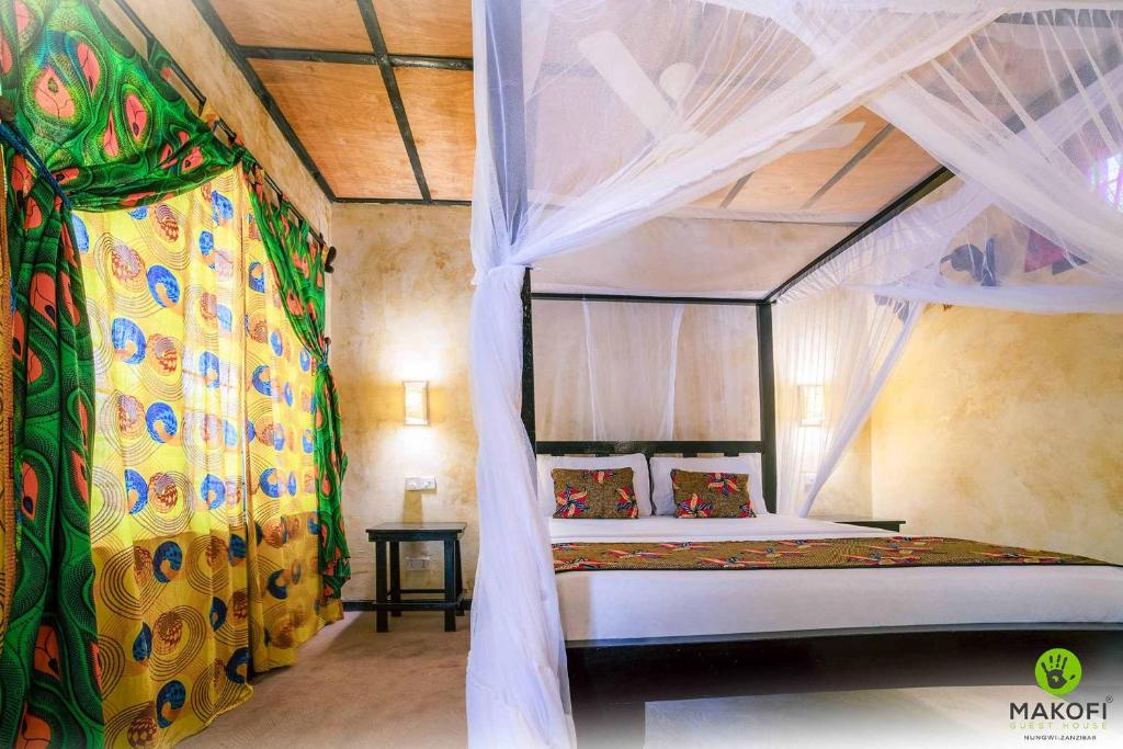 a bedroom with a canopy bed in a room at Makofi Guest House in Nungwi