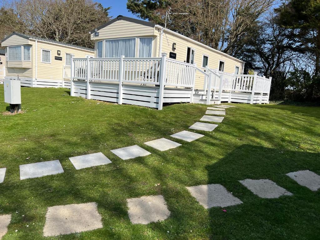 a house with a white fence and a yard at Forest beach Shorefield Park in Lymington