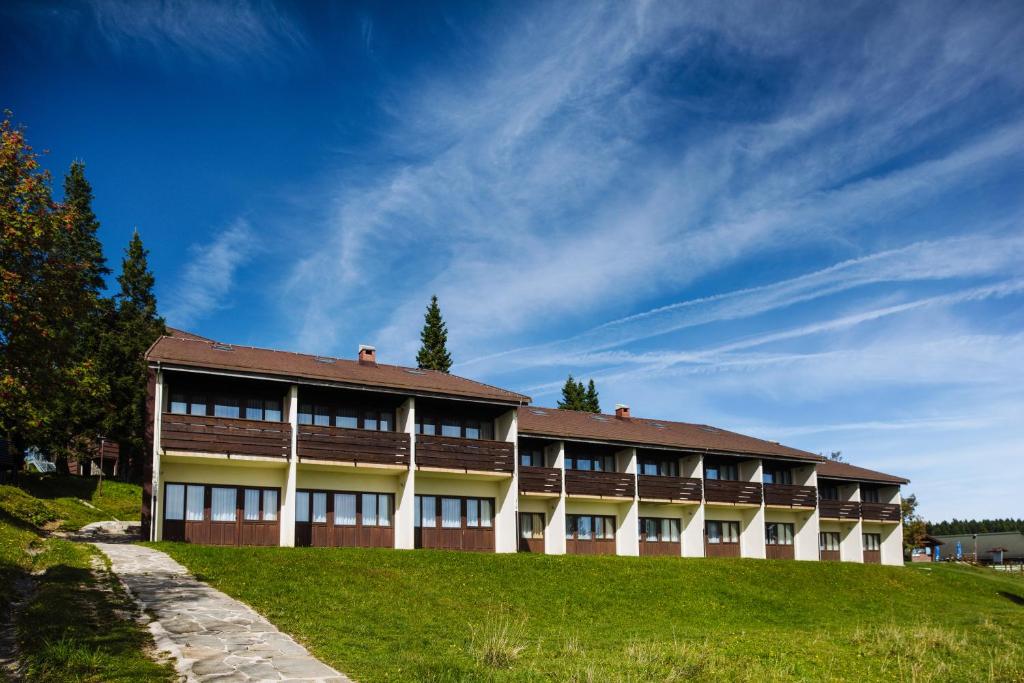 un edificio en una colina con un cielo azul en Hotel Brinje, en Zreče