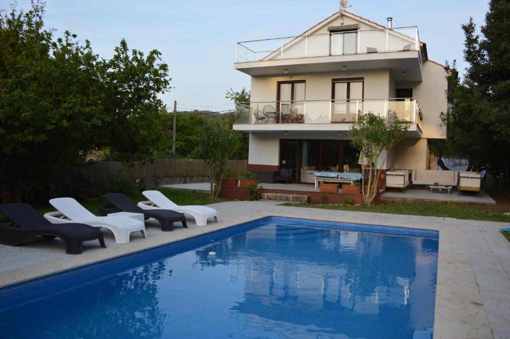 a villa with a swimming pool in front of a house at Sobreomar in Bueu