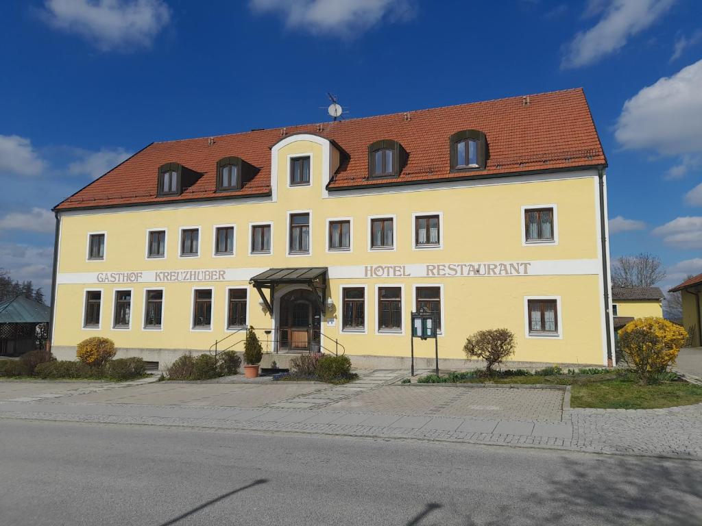 ein großes gelbes Gebäude mit rotem Dach in der Unterkunft Hotel-Restaurant Kreuzhuber in Neuburg am Inn