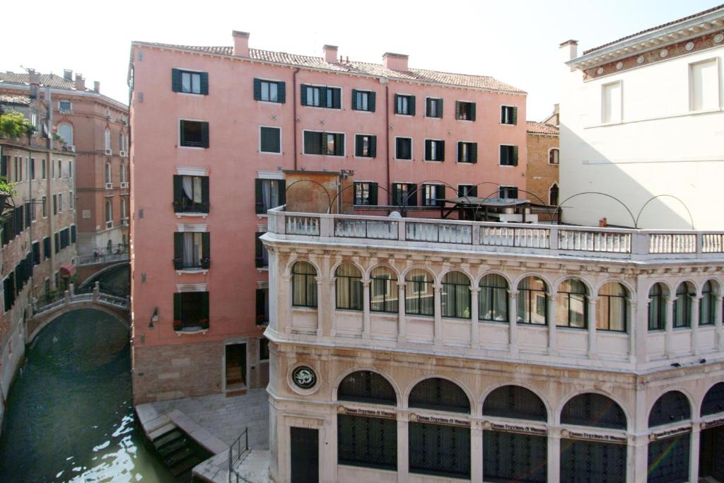 a building with a balcony next to a river at Residence Corte Grimani in Venice