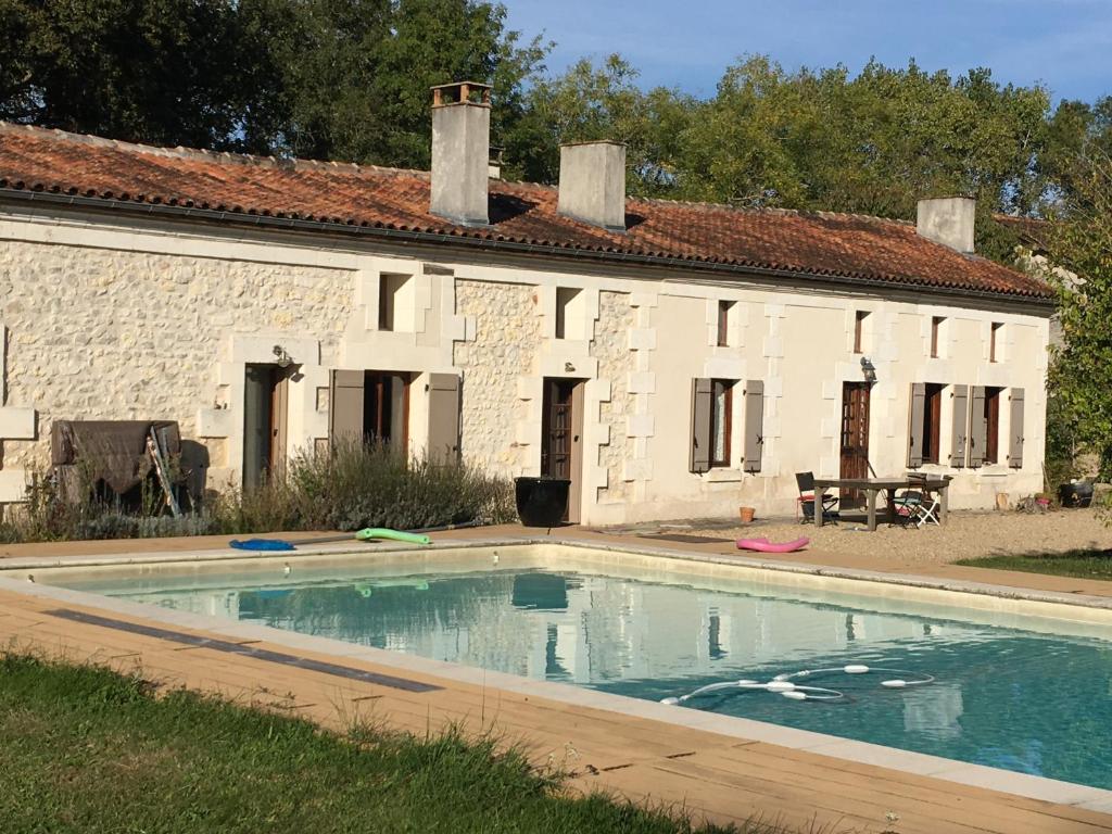 une maison avec une piscine en face d'un bâtiment dans l'établissement Maison Périgord vert piscine et spa, à La Roche-Chalais