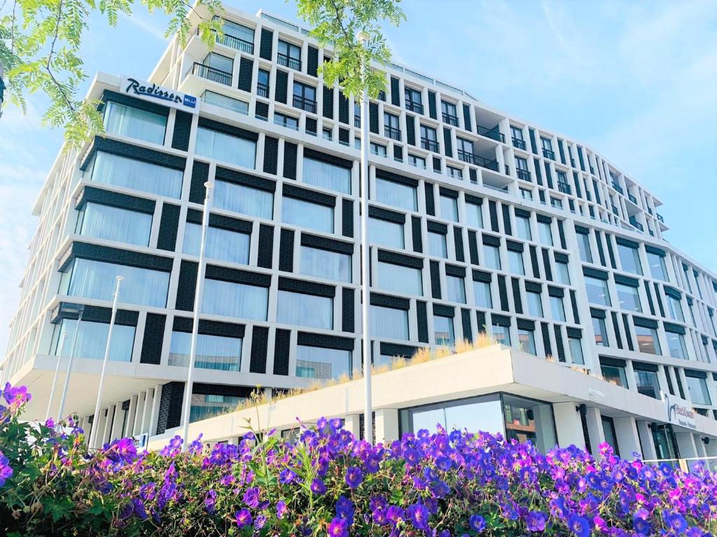 un immeuble de bureaux avec des fleurs violettes devant dans l'établissement Radisson Blu Hotel, Bruges, à Bruges