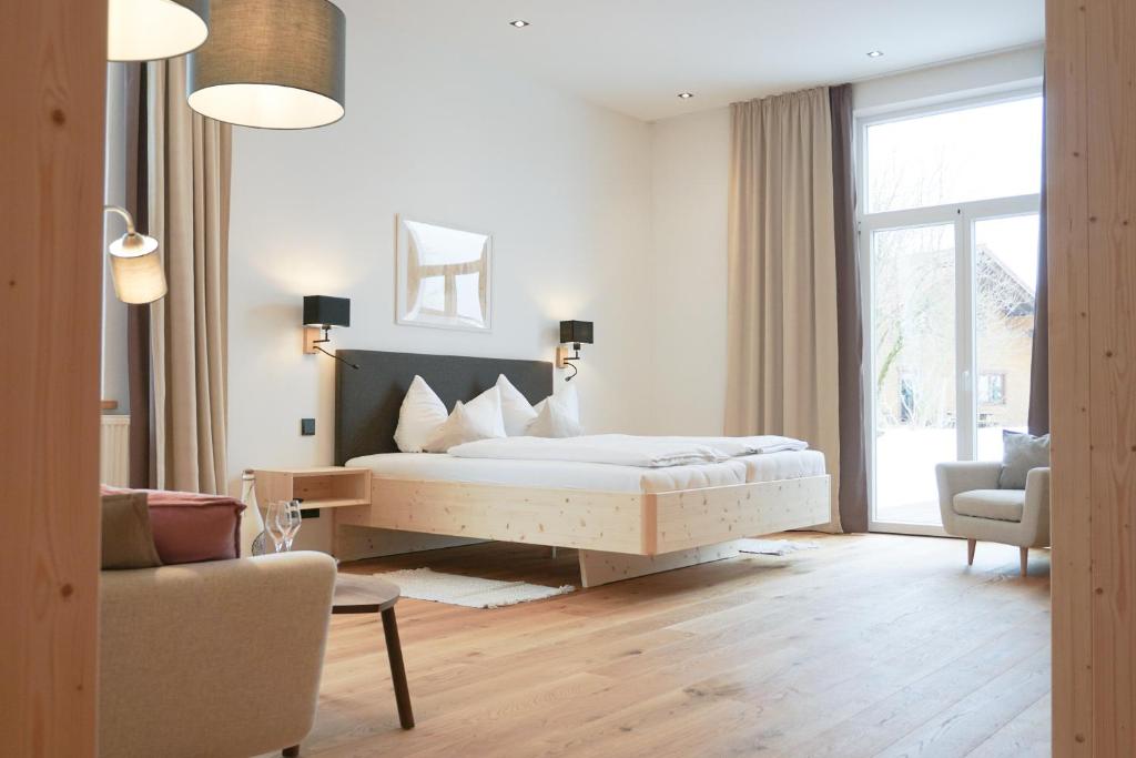 a bedroom with a bed and a couch and a chair at Landhotel und Gasthof Kirchberger in Wildsteig